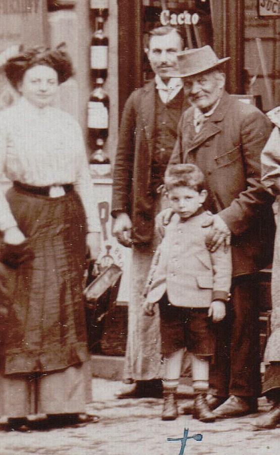 Karl König 1906 als kleiner Junge. Er steht mit Eltern und Nachbarn in Wien auf der Straße vor einem Laden.