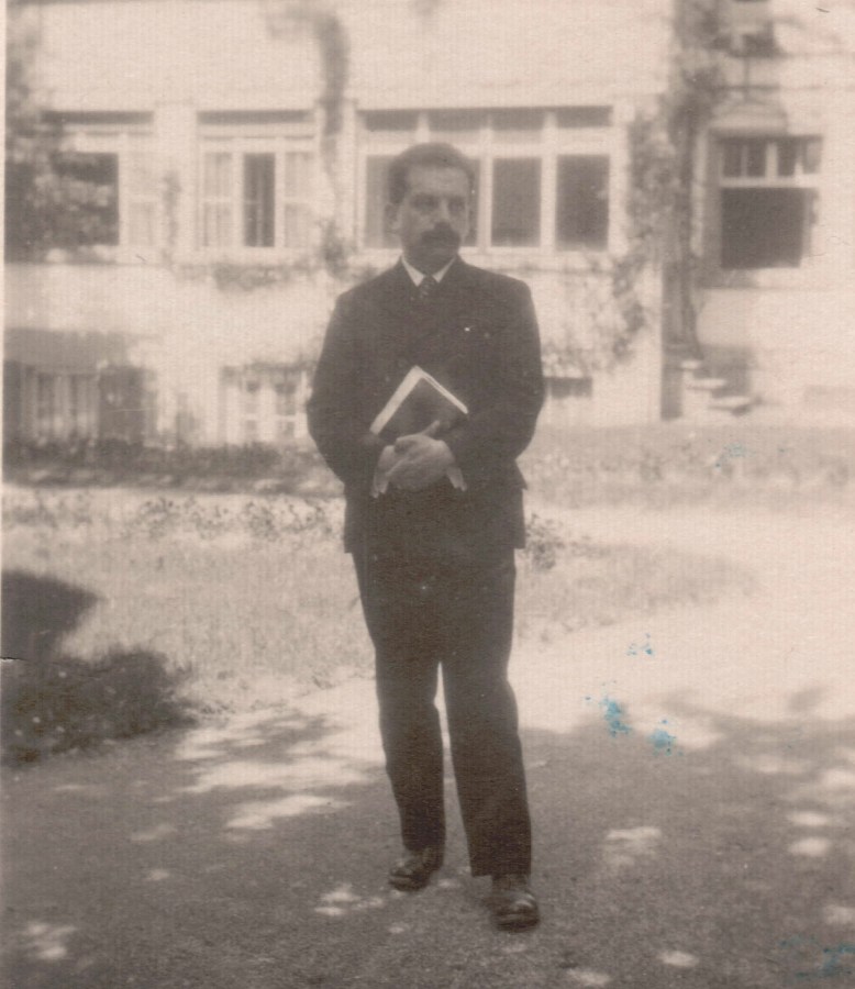 Karl König 1928 in Arlesheim (Schweiz). Er steht mit einem großen Buch in den verschränkten Händen vor einem Haus.
